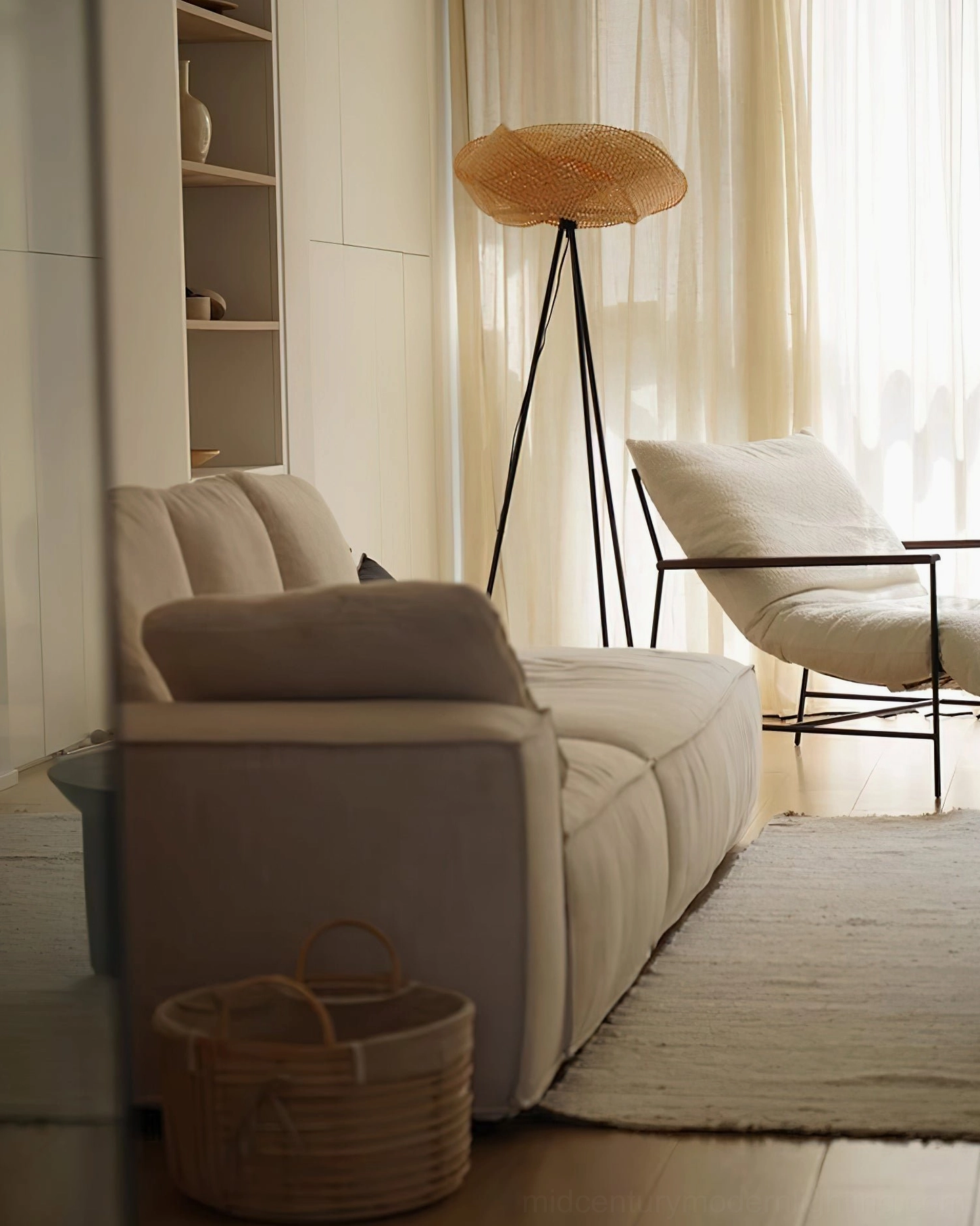Modern rattan floor lamp positioned near sheer window curtains in cozy living room with sofa and lounge chair, side perspective