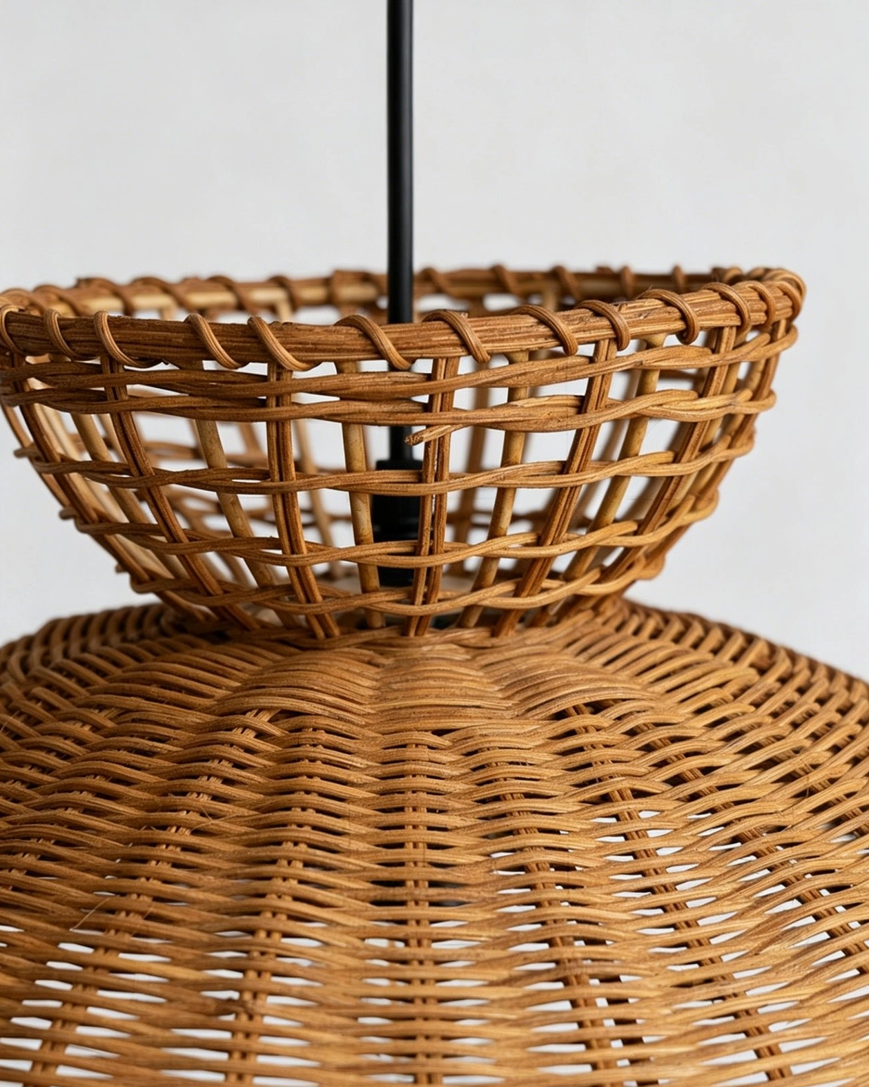 Bottom-up detail of rattan pendant light showing tightly woven basket construction and black metal suspension rod
