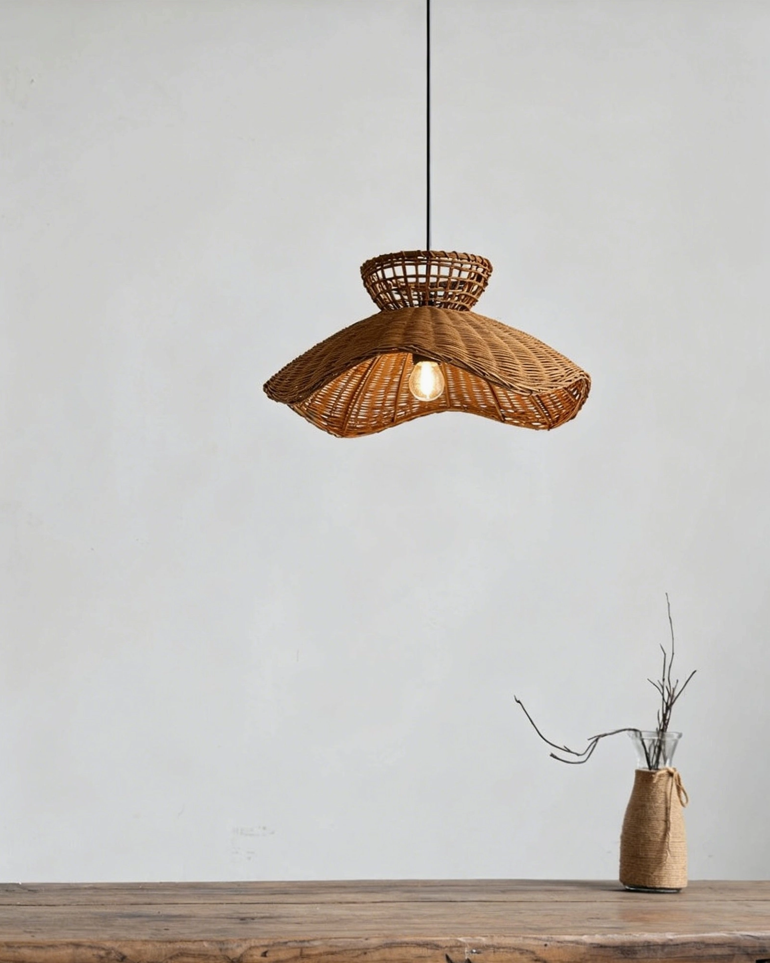 Front low angle view of rattan pendant light above wooden surface with dried floral arrangement