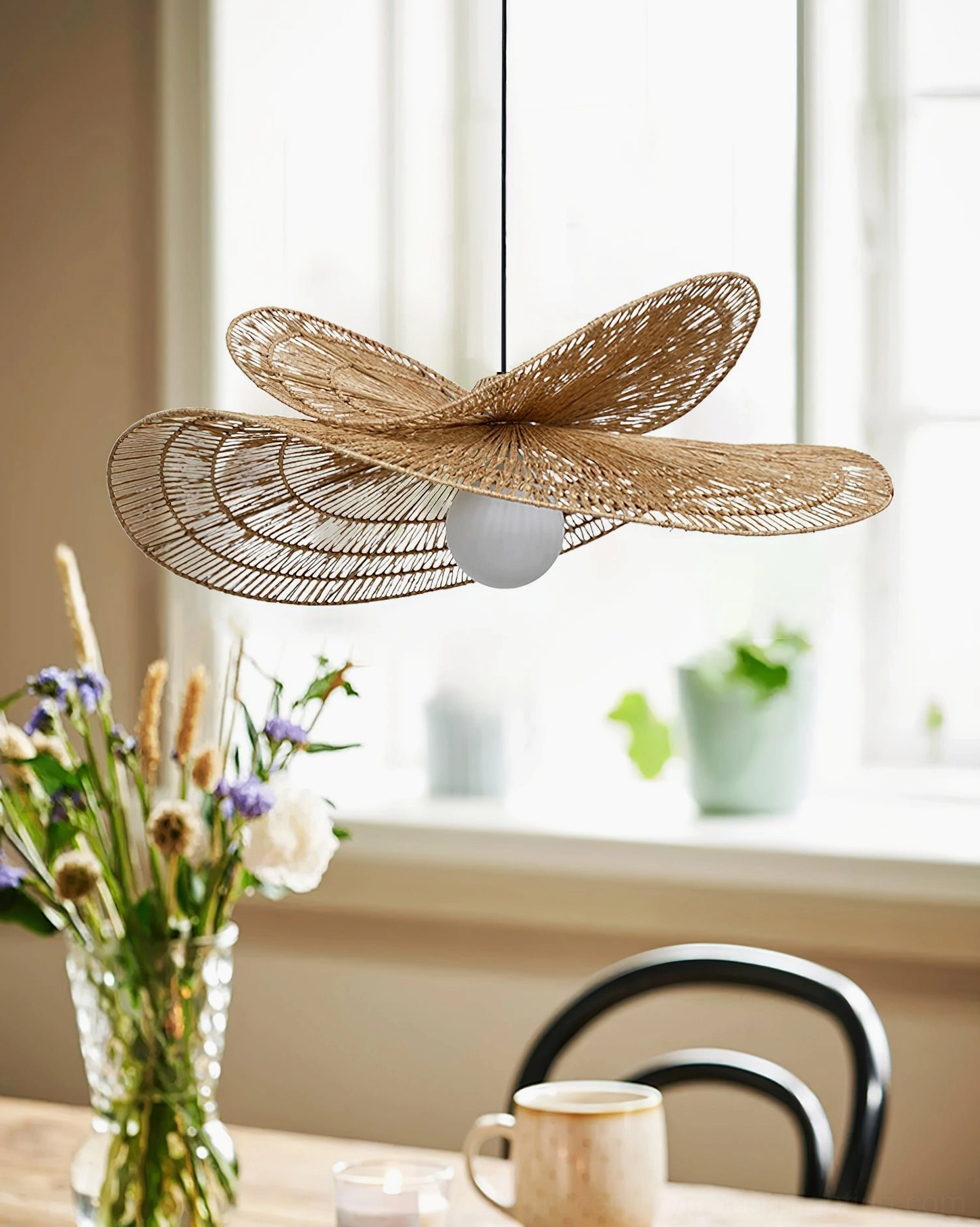 Close-up detail of handwoven rattan shade texture on petal pendant lamp positioned above dining table corner