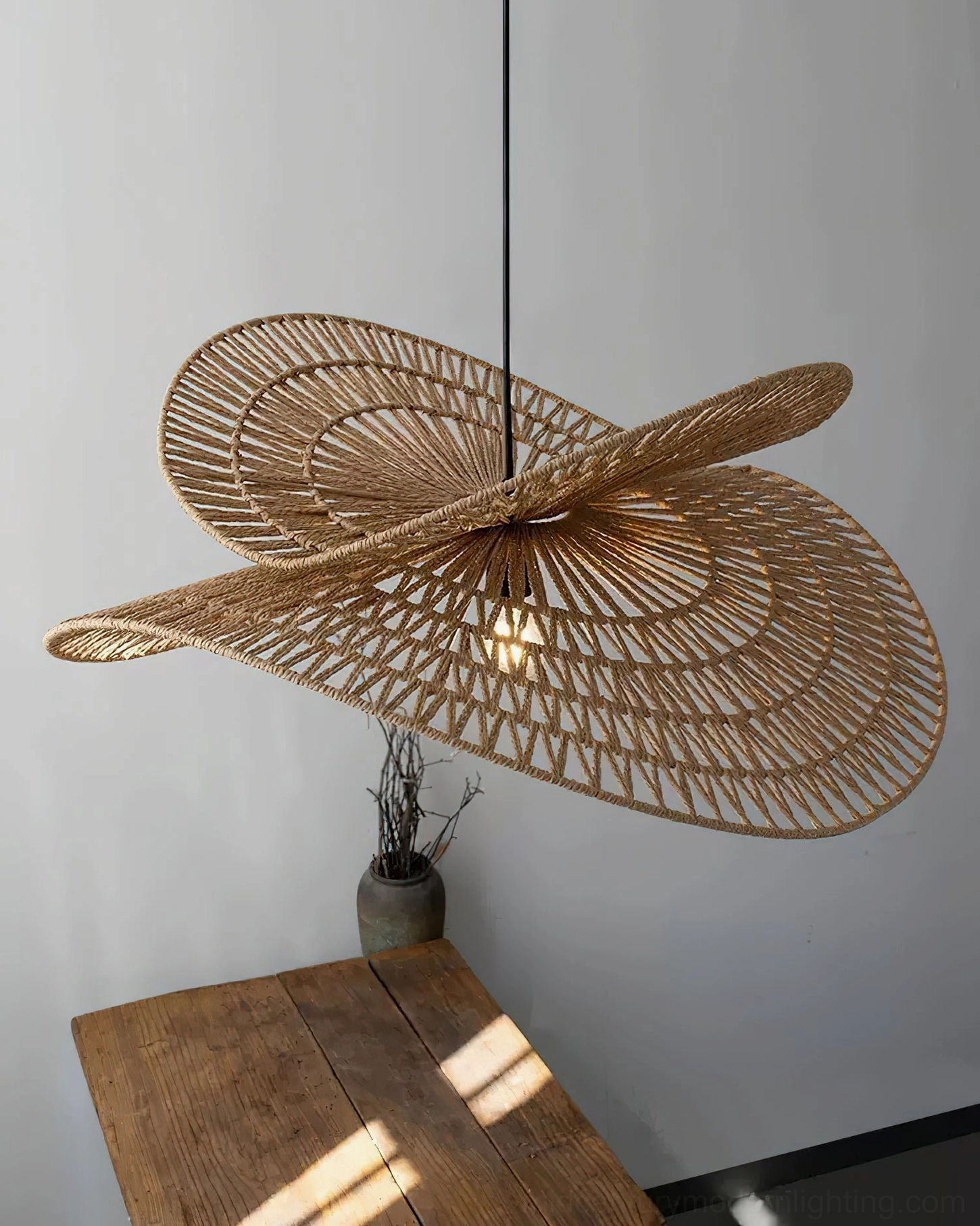 Special twisted woven rattan petal pendant shade on wooden studio table backdrop - artisanal craftsmanship