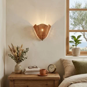 Sarasota rattan wall sconce installed above bedside table in coastal bedroom, casting warm patterned light