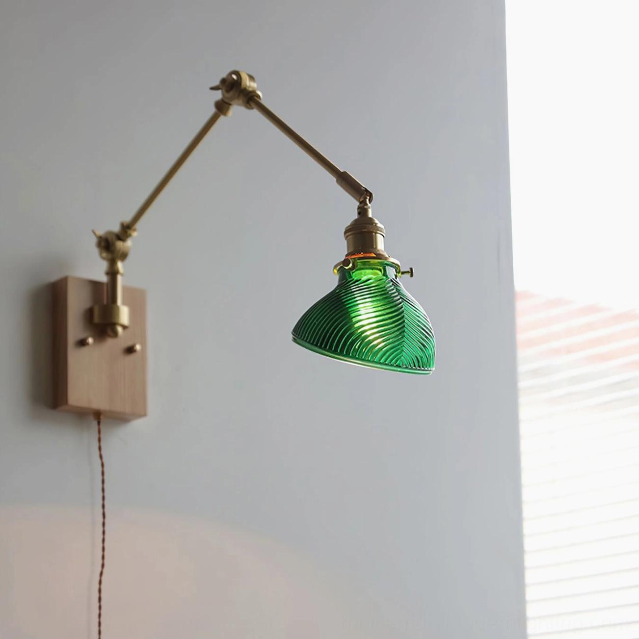 Rebell plug-in swing arm wall lamp with light wood base and green ribbed glass shade, front view in home with sheer curtains