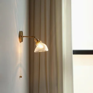 Rebell pull-chain wall lamp side view with clear ribbed glass shade illuminated by window light