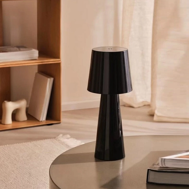 Black modern table lamp displayed on round side table with stacked books in contemporary living room
