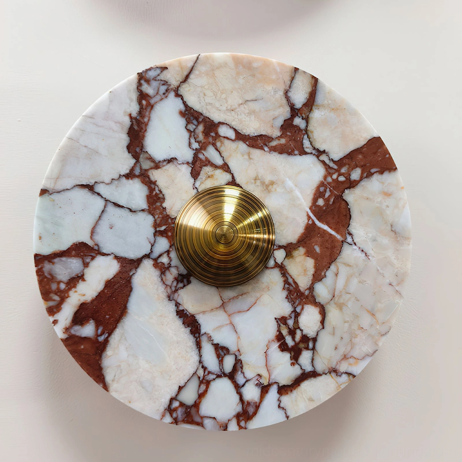 Red and white marble geometric wall lamp with brass hardware on beige interior wall showing warm stone tones