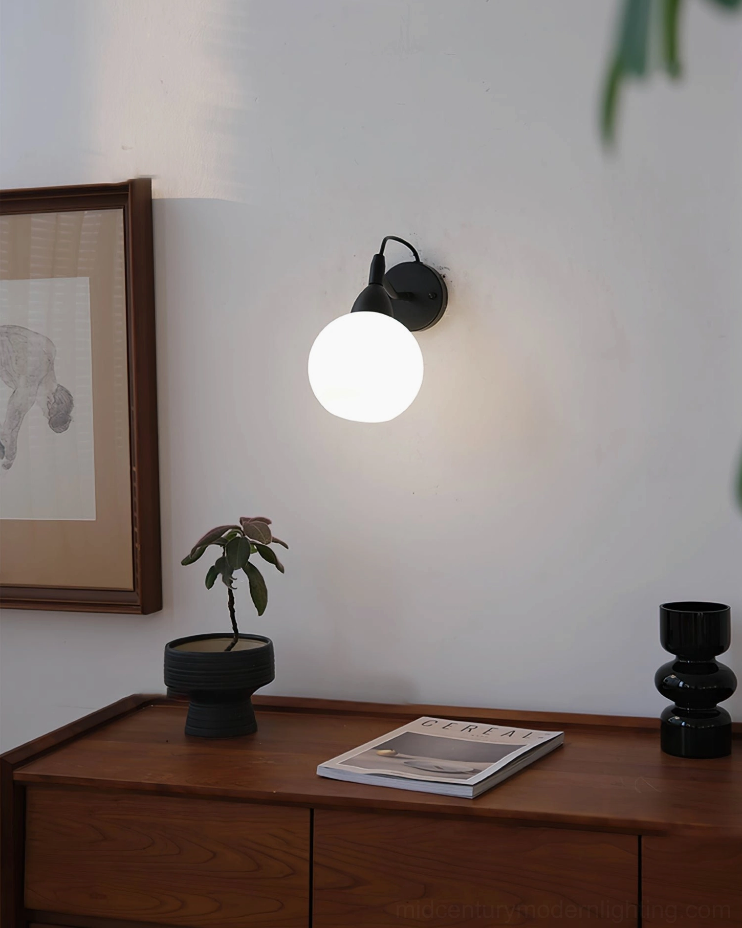 Reese illuminated wall lamp distant eye-level view on wooden console with home decor and framed artwork