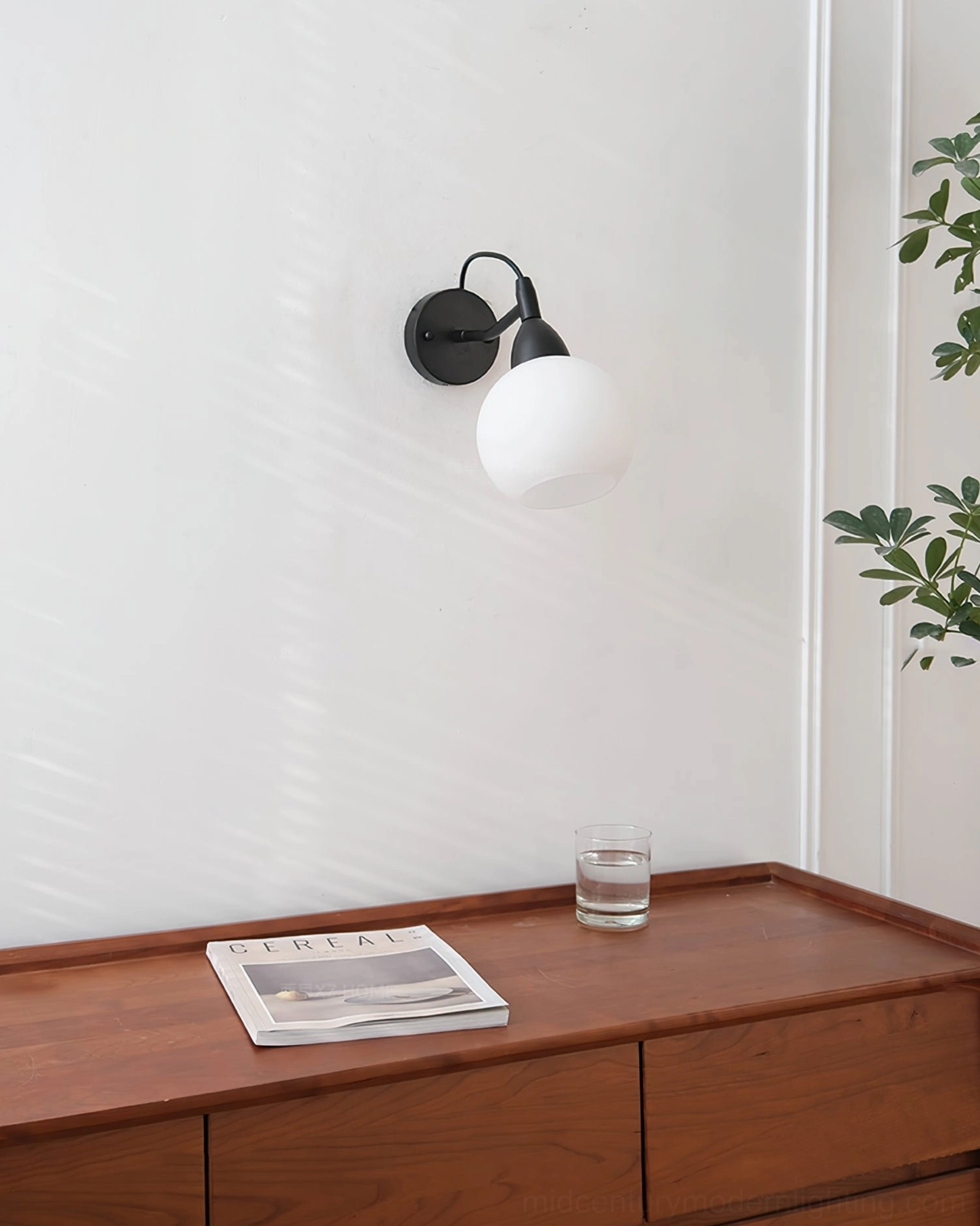 Reese lit wall mounted sconce distant side view on wooden sideboard with decorative plants and accessories