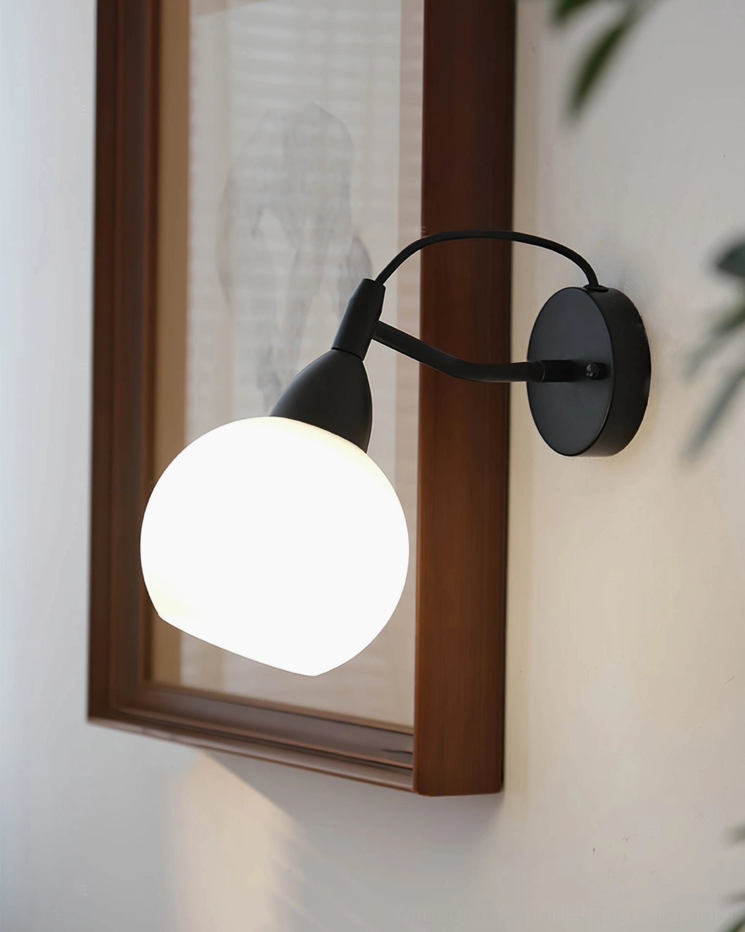 Reese illuminated spherical wall lamp low angle view beside framed wall art with warm ambient glow