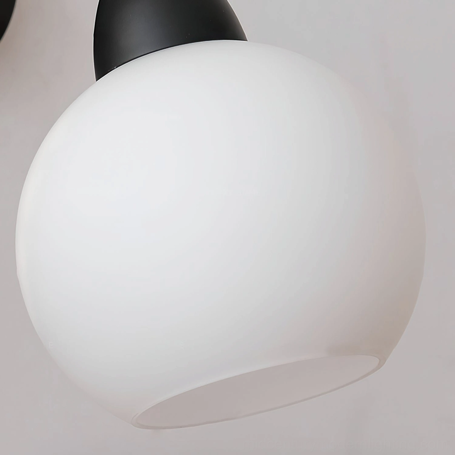 Reese modern wall sconce close-up highlighting curved black arm and globe glass diffuser design
