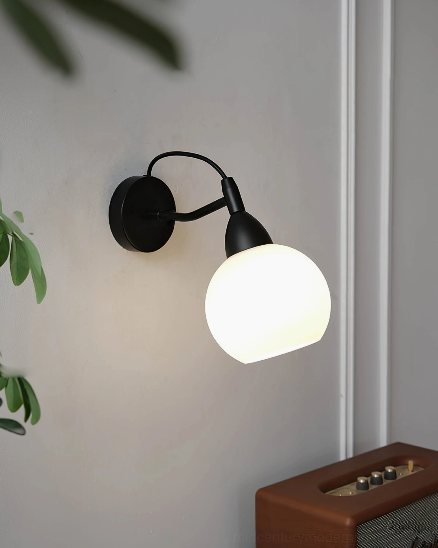 Reese modern spherical wall sconce low front side view in living room with vintage radio and warm neutral decor