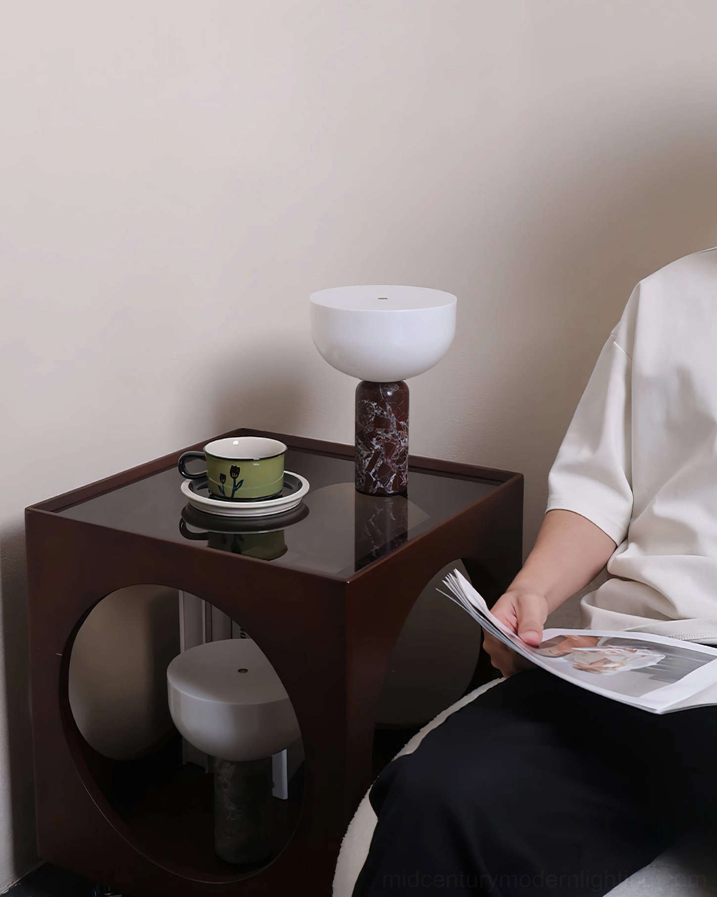 Person relaxing and reading with reddish brown Renard marble table lamp in cozy living room setting