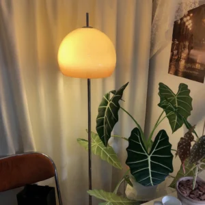 Mid-century modern mushroom lamp placed in home corner with warm ambient lighting near green plant