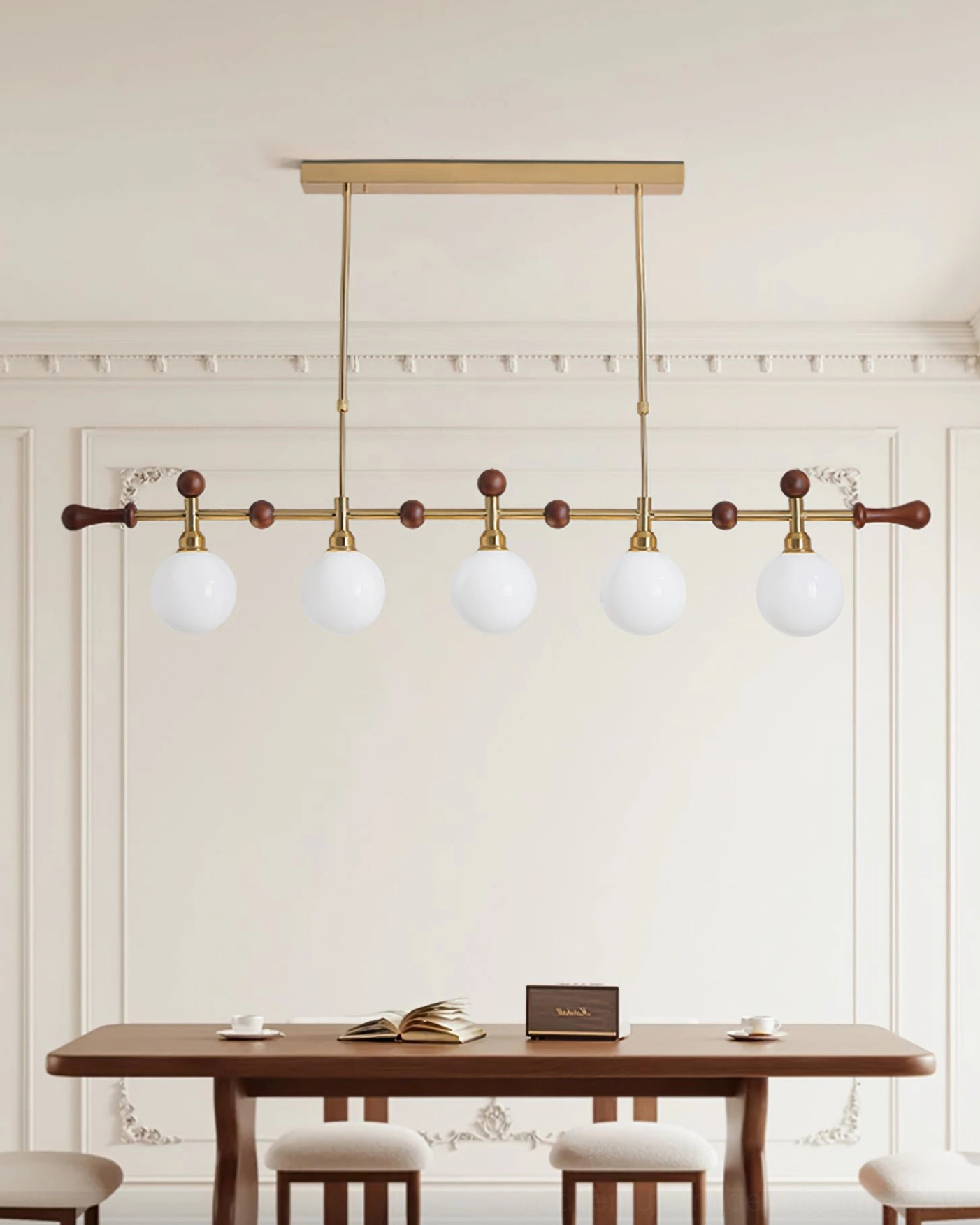 Reya 5-head linear chandelier installed above long wood dining table in French classic dining room, elegant neutral interior