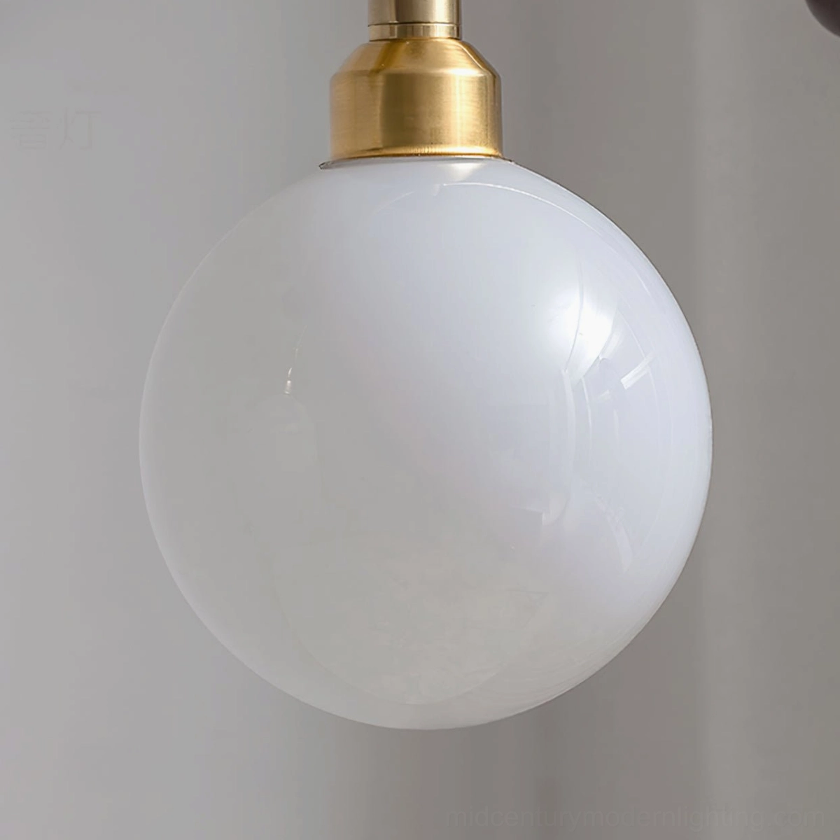 Close-up detail of Reya linear chandelier lamp base showing polished brass gold fixture and frosted opal white glass globe