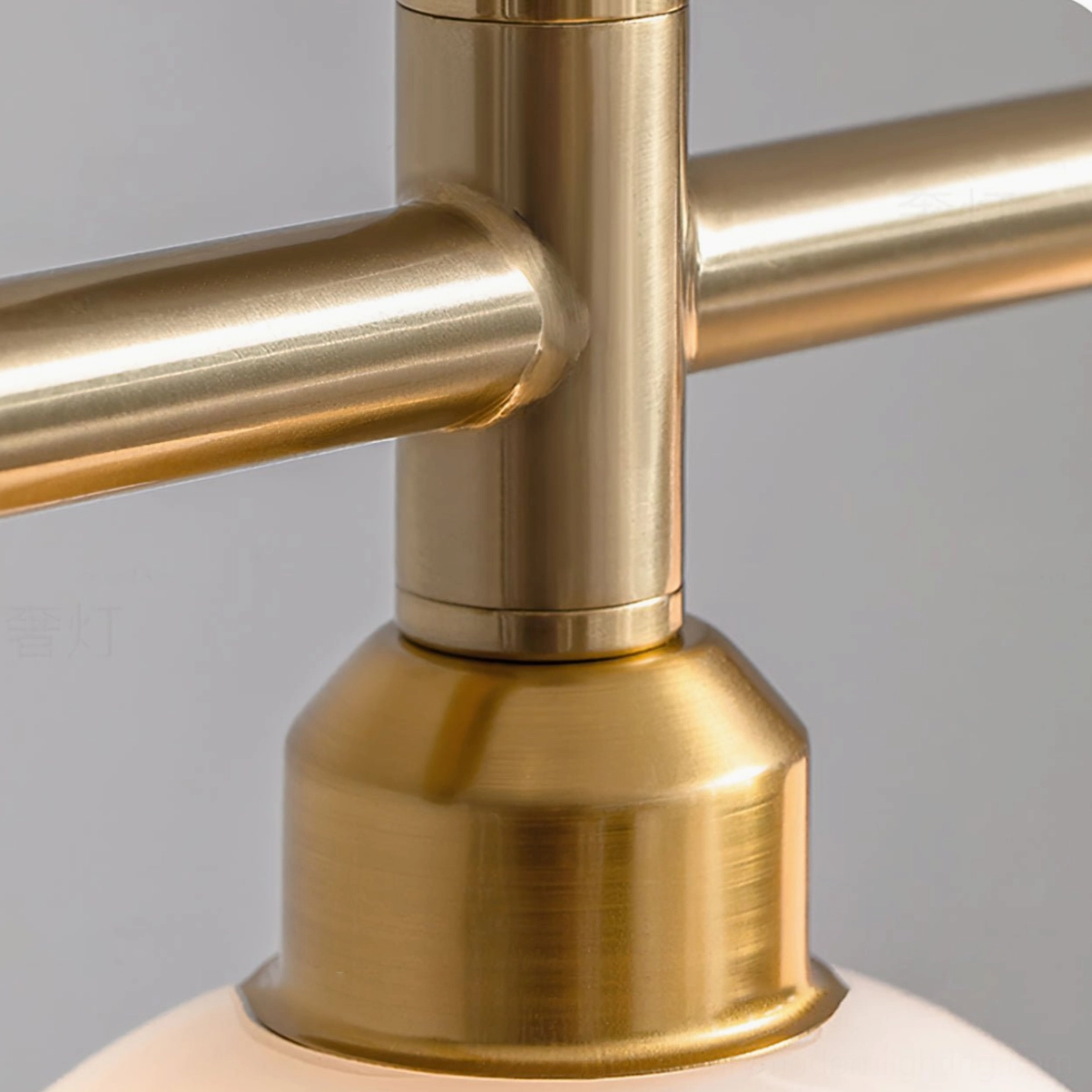 Macro detail of Reya linear chandelier metal joint showing brushed brass gold tubing and sturdy connection hardware