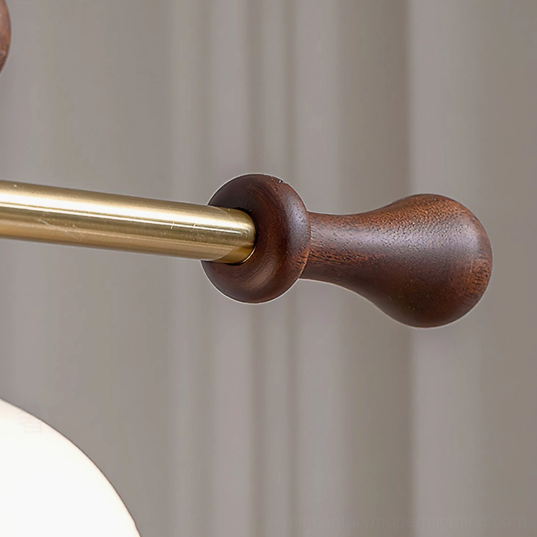 Close-up detail of Reya linear chandelier walnut wood accent end cap with brass gold metal rod connection