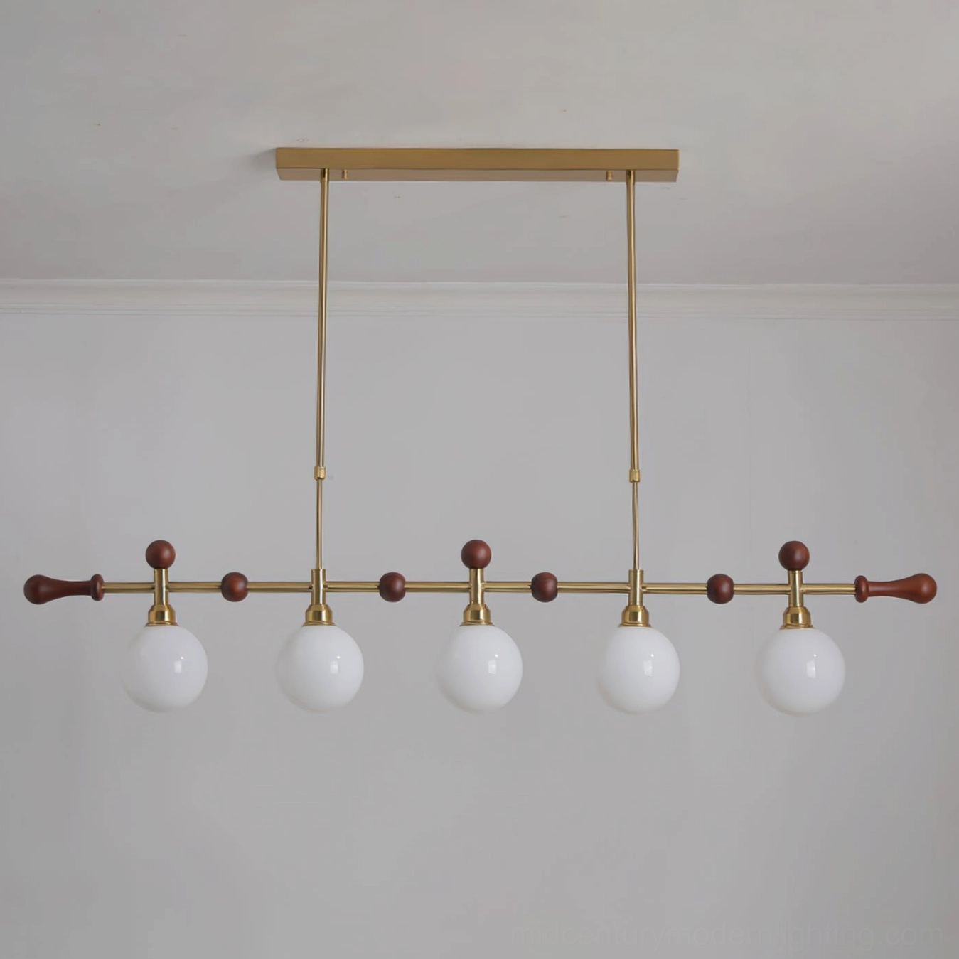 Reya linear chandelier in contemporary interior setting, brass gold framework with opal white glass shades creating soft ambient lighting