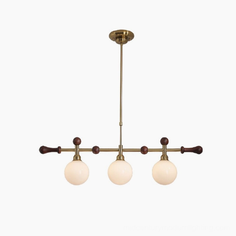 Full view of Reya linear chandelier showcasing elongated brass metal frame, multiple frosted glass globes, and dark wood accent details