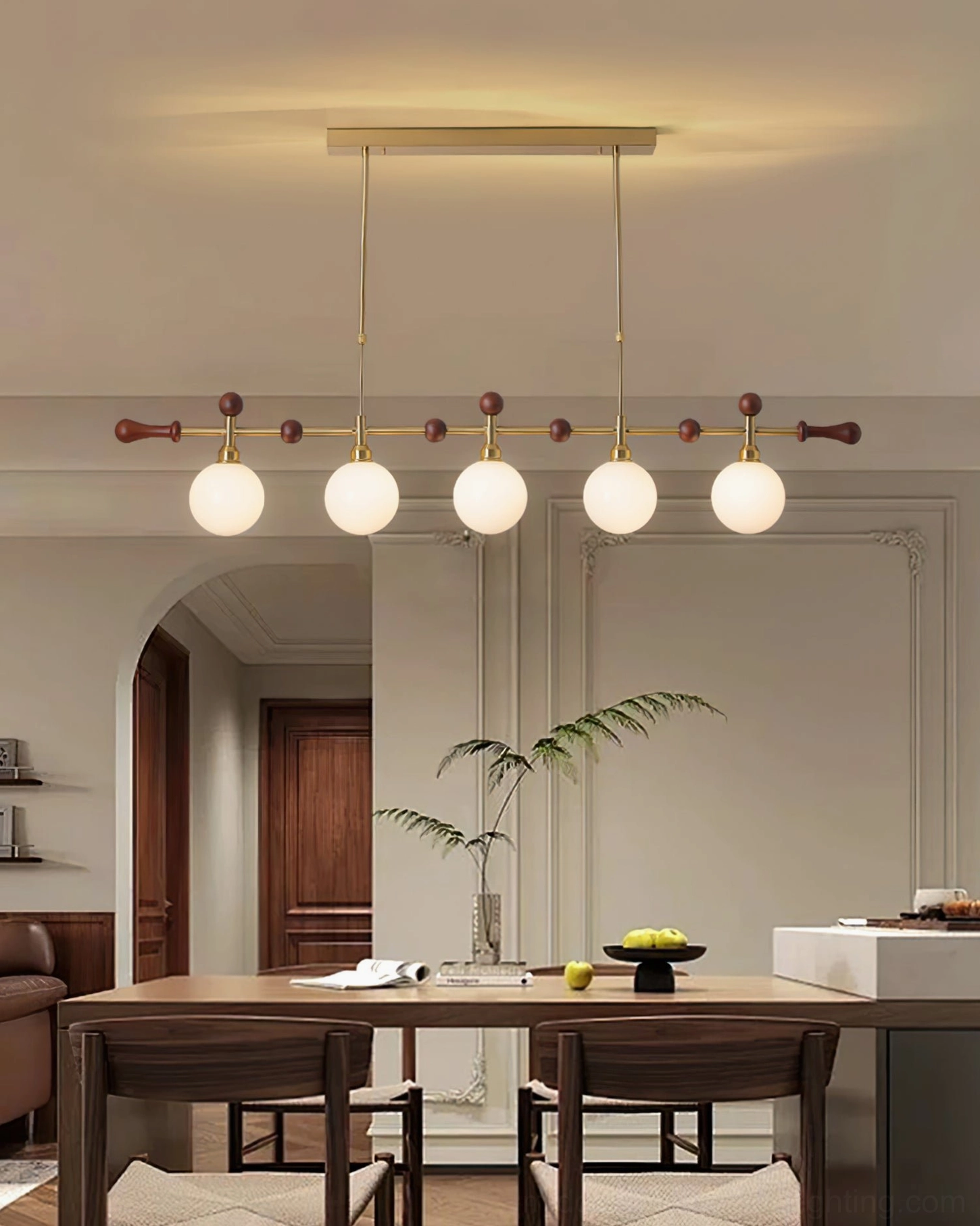Lit Reya linear chandelier with glowing glass globes in open concept dining-living room, cozy brass and wood design details