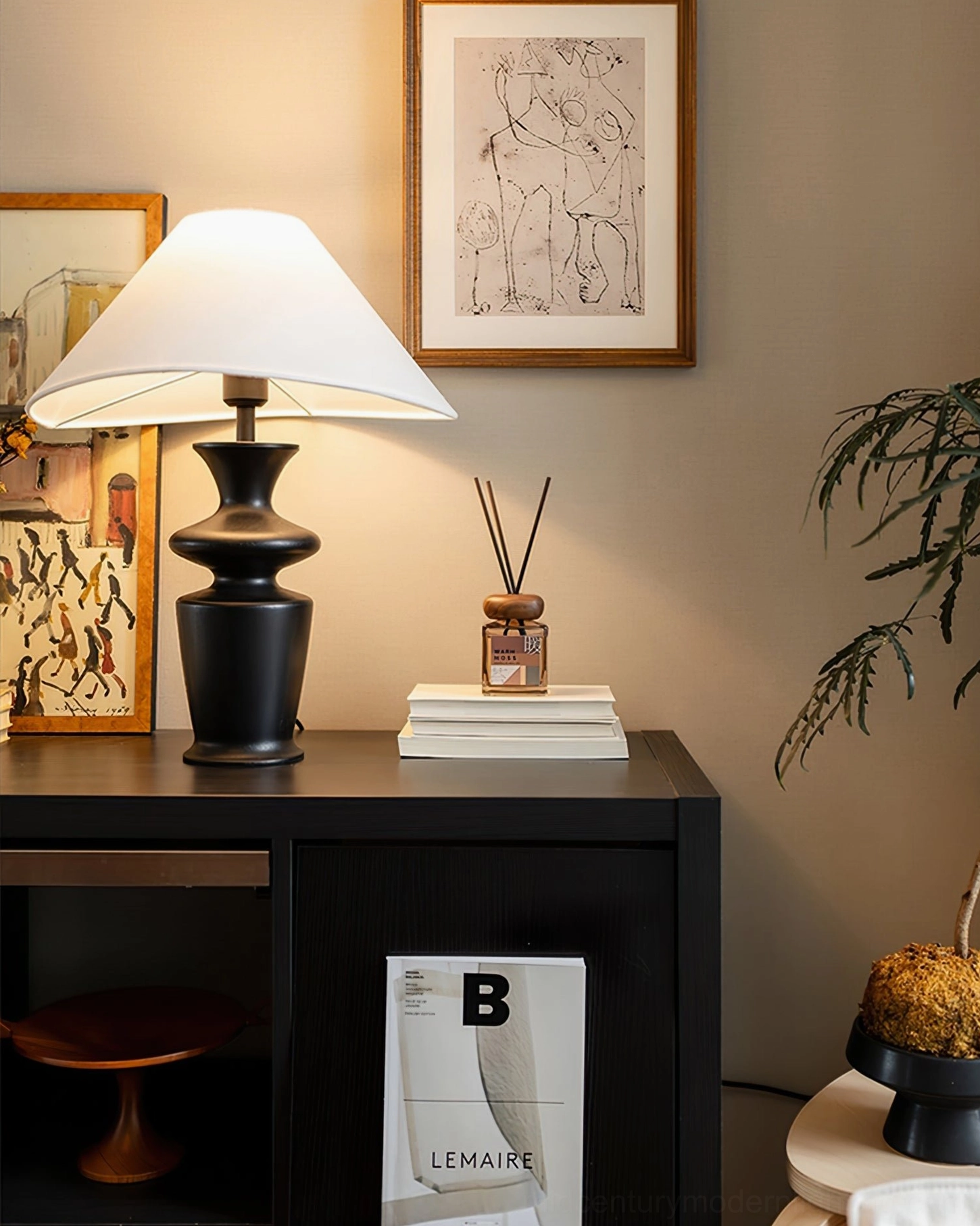 Rhodes sculptural lamp on black wooden side cabinet with books and decorative accessories nearby