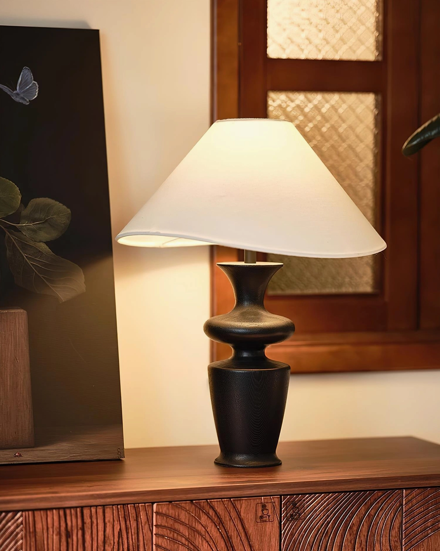 Rhodes mid-century modern lamp with black sculptural base and white fabric shade on wooden cabinet