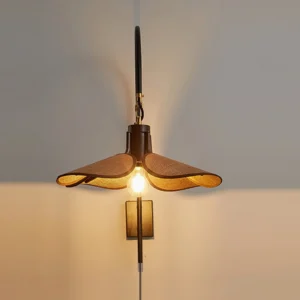 Riankh plug-in wall lamp eye-level close-up view mounted on indoor wall showing curved black metal arm with warm ambient lighting effect