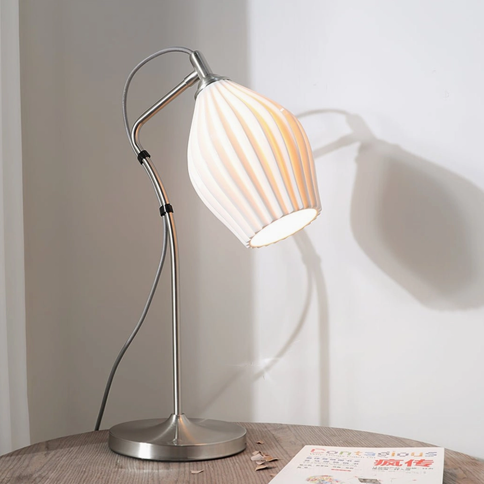 Ribbed ceramic table lamp low front view with warm cast shadow on blank interior wall, minimalist aesthetic