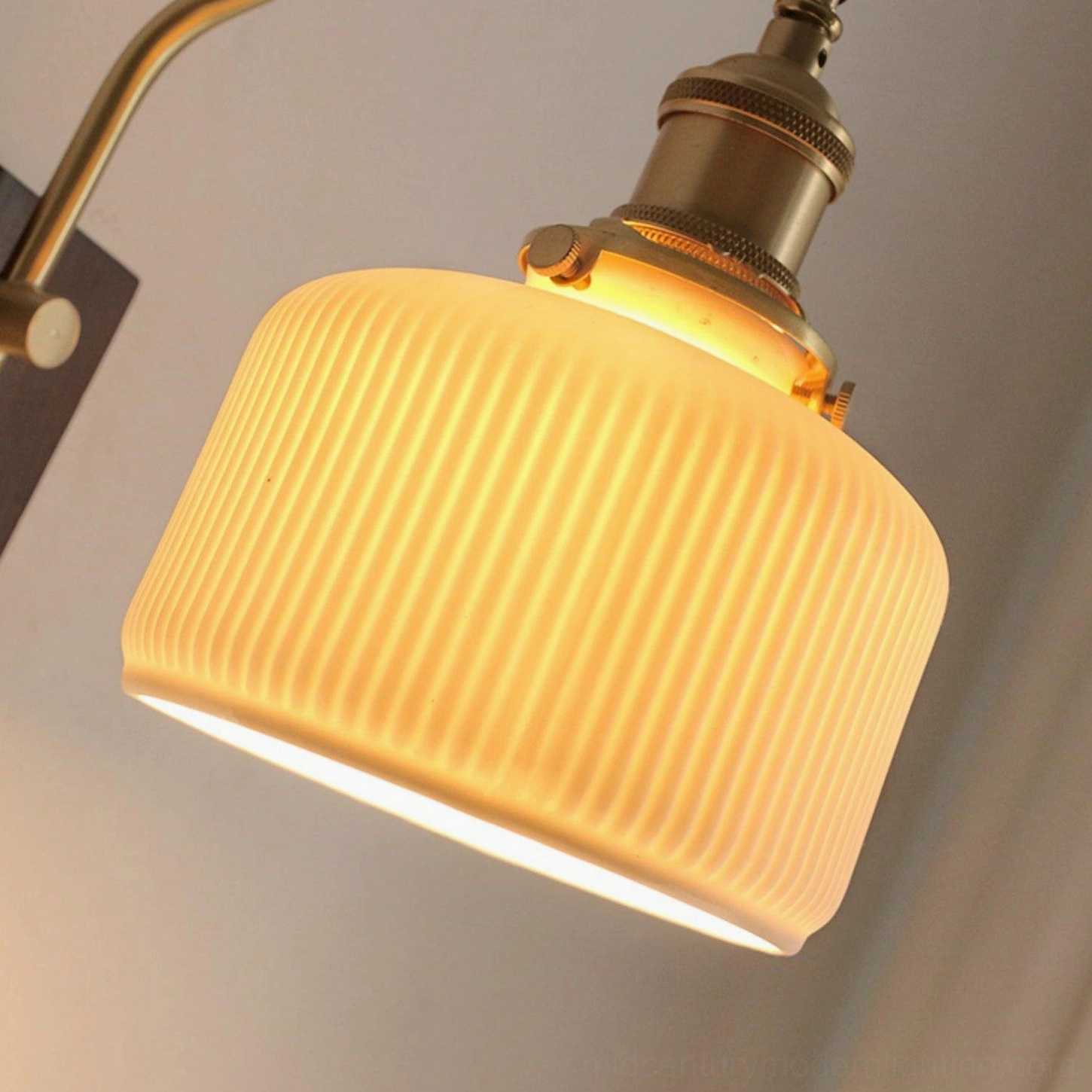 Detailed close-up of vertical ribbed ceramic shade with warm glowing light creating ambient atmosphere