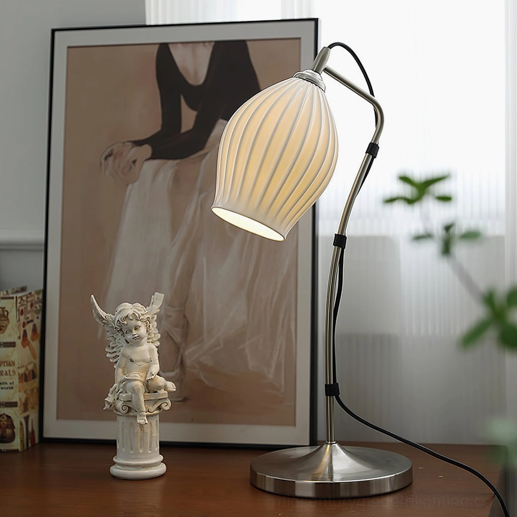 Silver ribbed table lamp on vintage home desk with angel statue and art painting, warm ambient lighting