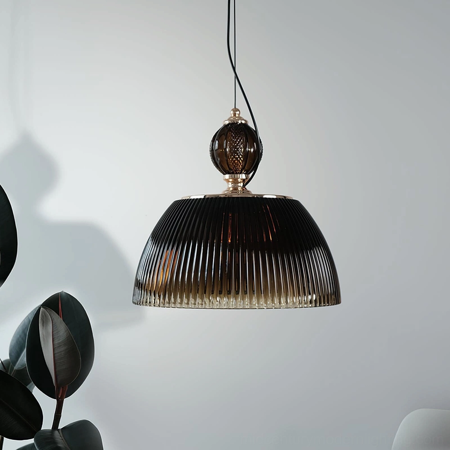 Hanging ribbed glass pendant with smoky brown gradient shade casting shadows on light gray wall - side view