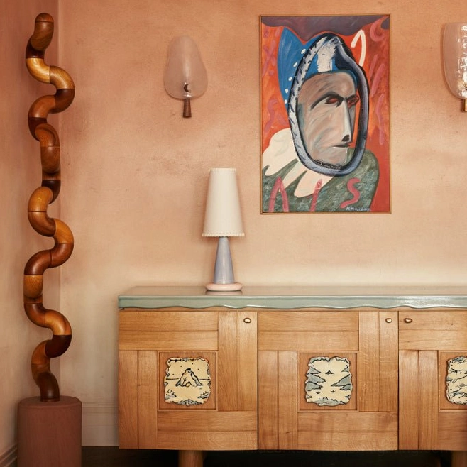 Ribbon table lamp styled in vintage eclectic home interior on wooden sideboard with artistic wall art and warm-toned wall