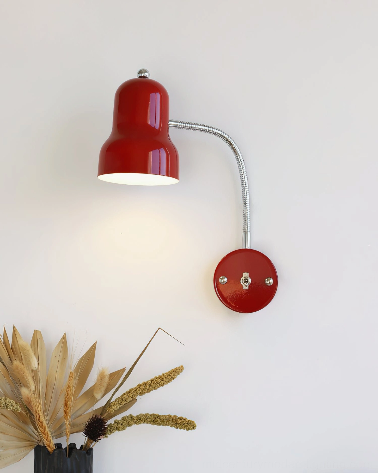 Illuminated Richard industrial wall lamp with polished metal gooseneck, three-quarter angle with home decor