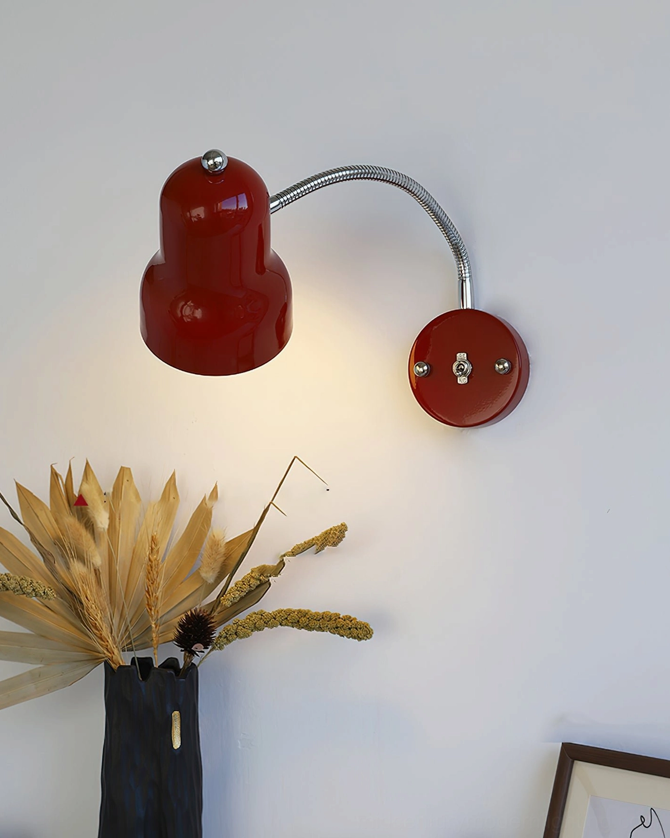 Red wall reading lamp mounted on white surface with downward-angled illuminated shade, botanical styling