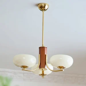 Three-light Rico pendant chandelier with polished brass hardware and brown wood central column, close-up ceiling view