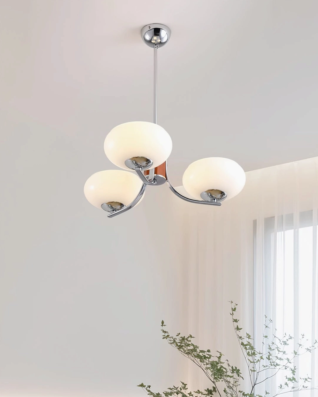 Three-light Rico modern pendant chandelier with silver metal arms in bright minimalist room with plant