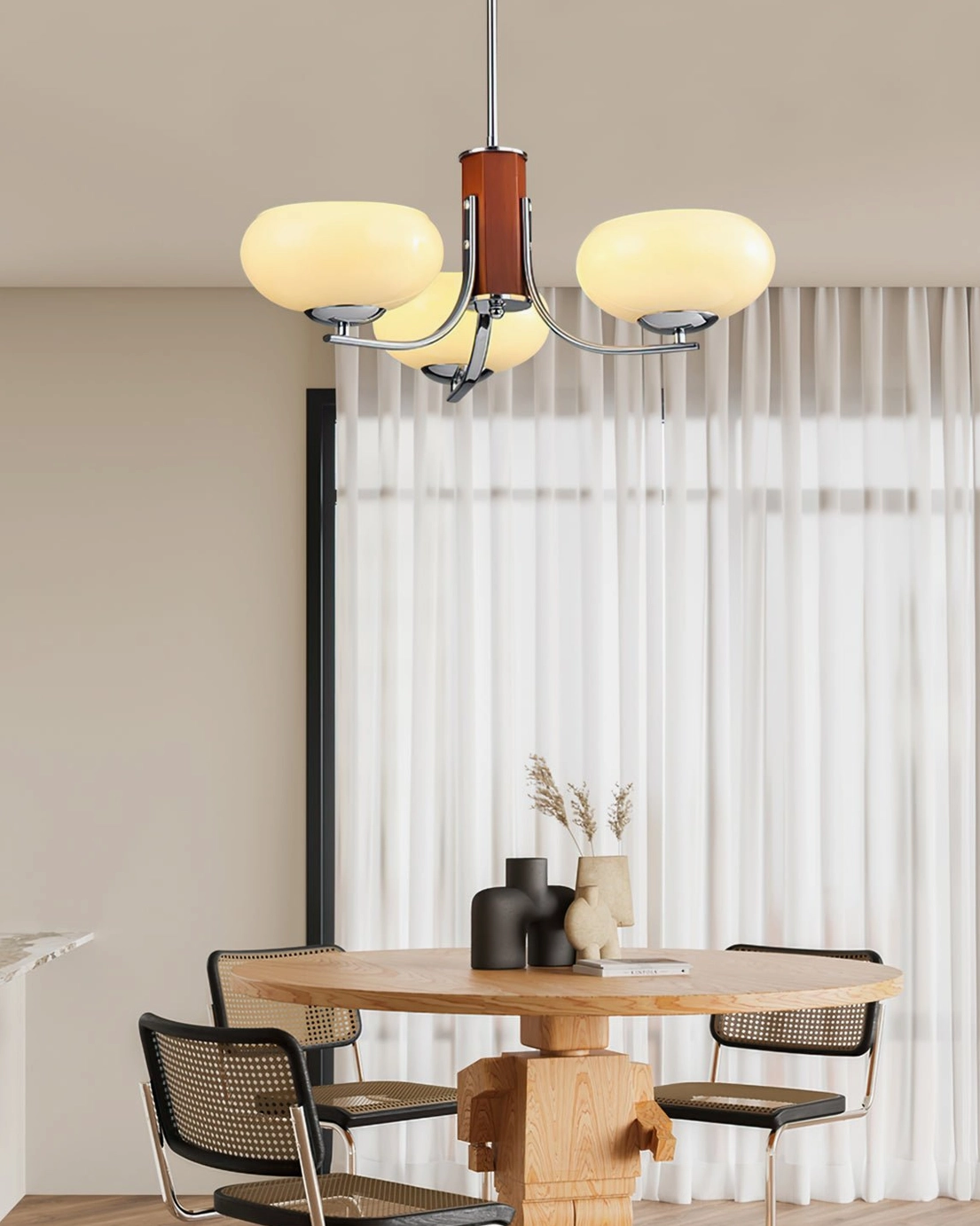 Mid-century Rico chandelier in modern dining room with round wooden table and sheer curtains