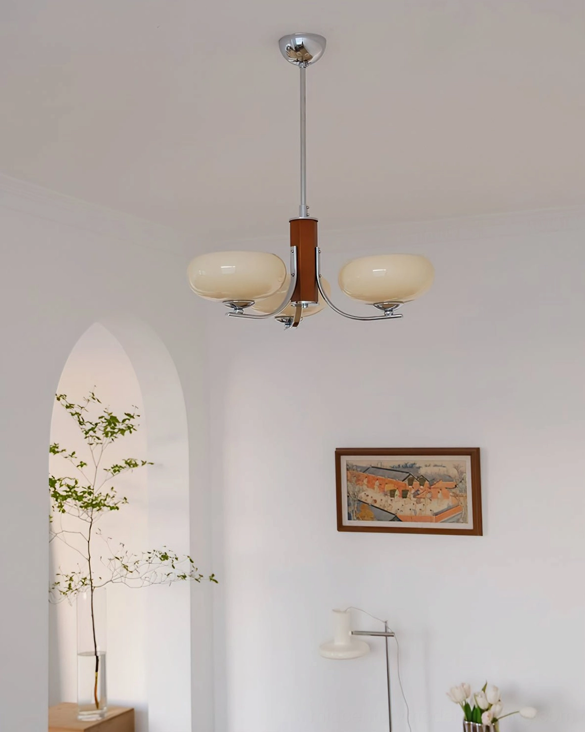 Chrome and wood Rico chandelier mounted in minimalist white living room with arched niche wall art