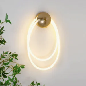 Rigel modern wall sconce with warm LED glow mounted on interior wall with green plant decor