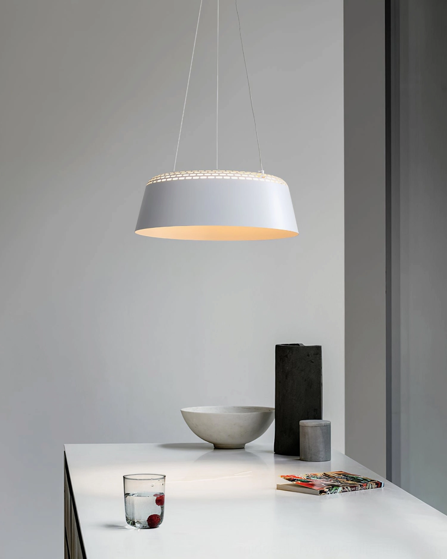 Ring white pendant light above modern kitchen dining counter with neutral tabletop décor and warm illumination