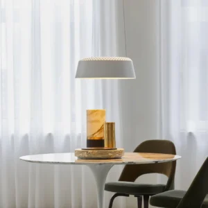 Ring white pendant lamp side view above dining nook with warm ambient illumination and sheer curtain backdrop