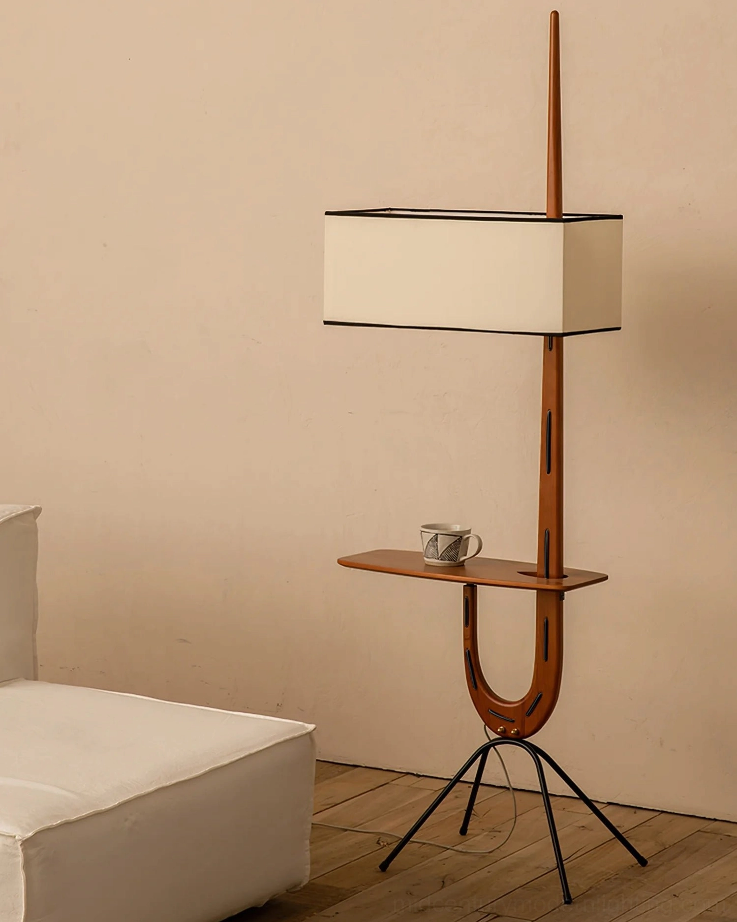 Coffee mug and accessories on Rispal Floor Lamp integrated console shelf, three-quarter side view with white fabric sofa backdrop
