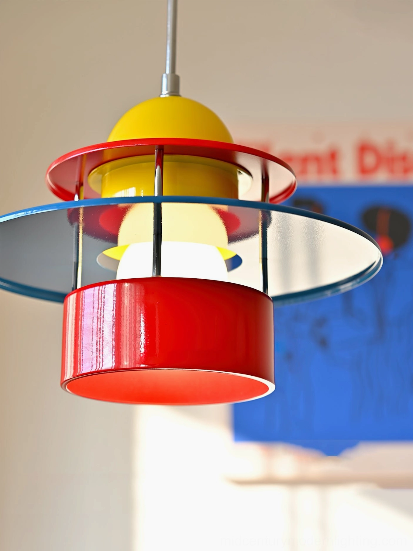 Rolly design pendant light low angle perspective showing translucent blue disc and metal support structure against art wall