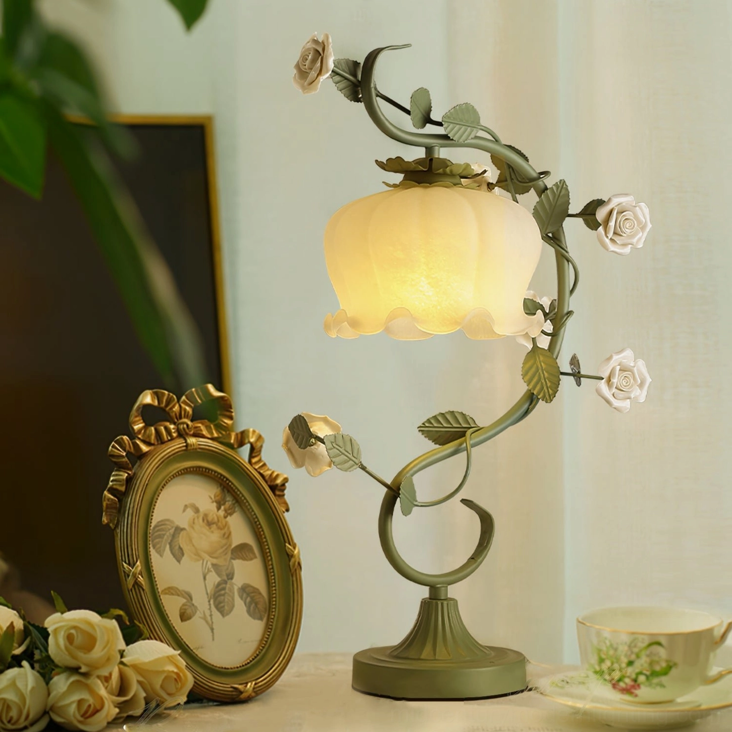 Rose vine table lamp beside teacup set and vintage frame on romantic country French home table