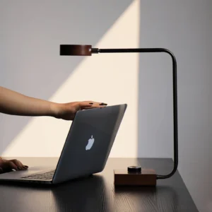 Rondo minimalist desk lamp in home office setting, warm LED light illuminating workspace with laptop and keyboard