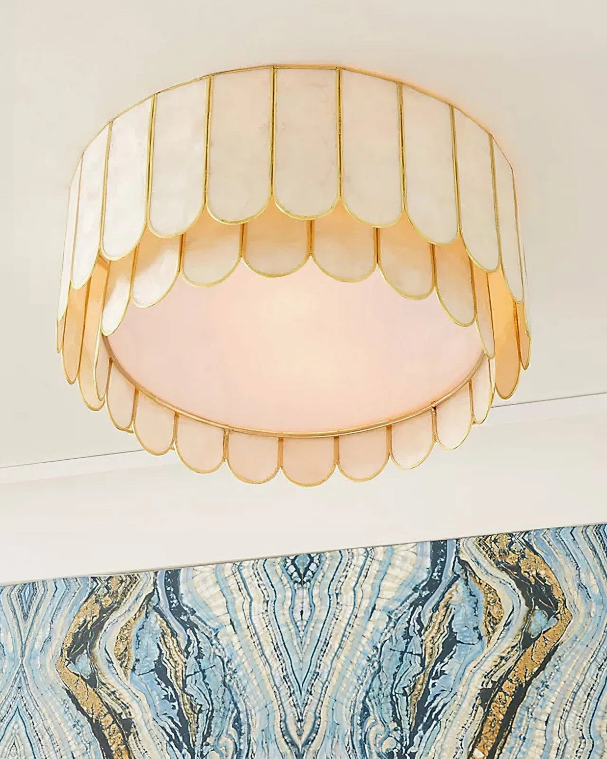 Rosa Capiz illuminated ceiling lamp glowing with warm white light, showing scalloped form and cream and gold color scheme