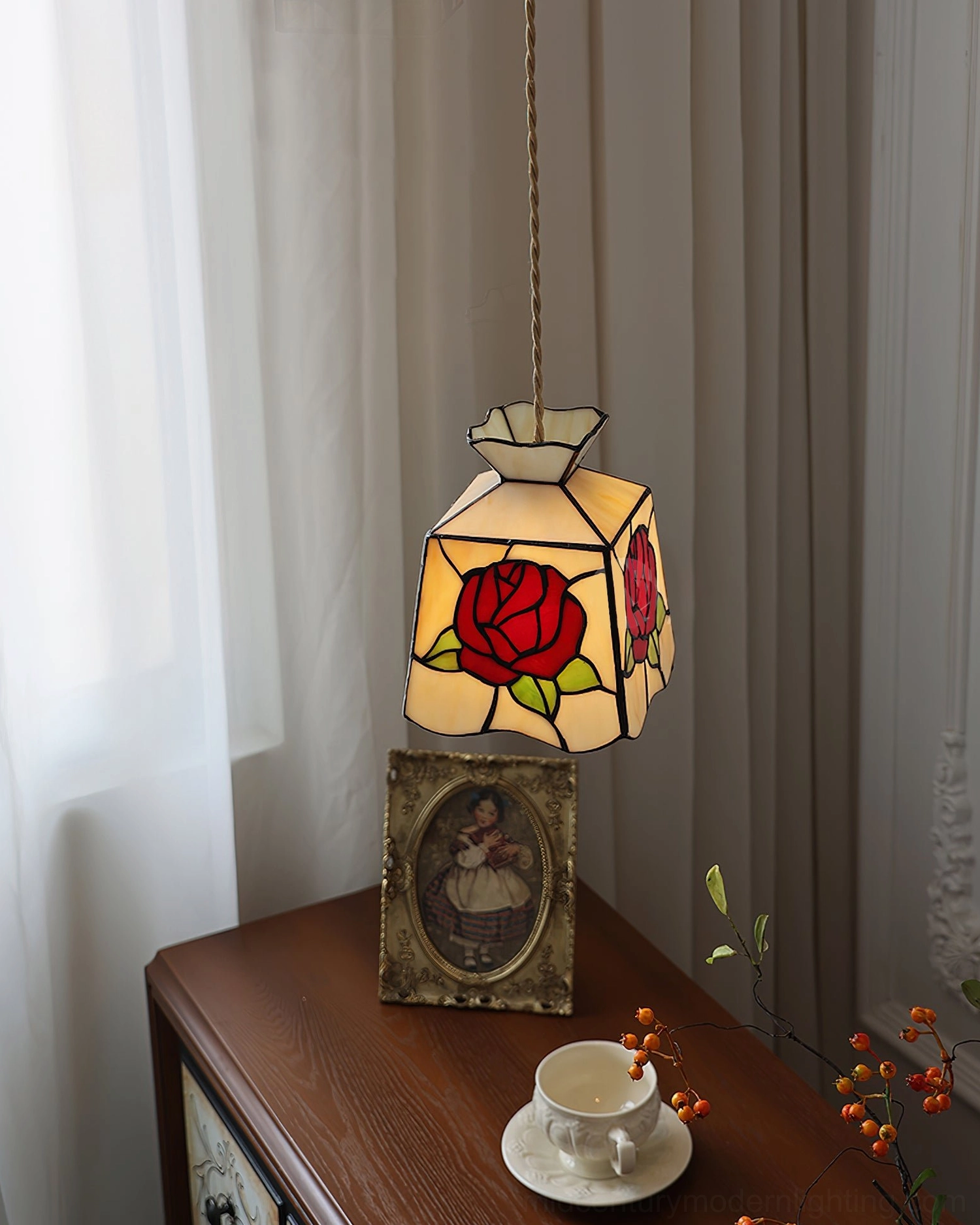 Handcrafted rose pendant light illuminating above wooden side table with coffee set, framed art and botanical branch styling