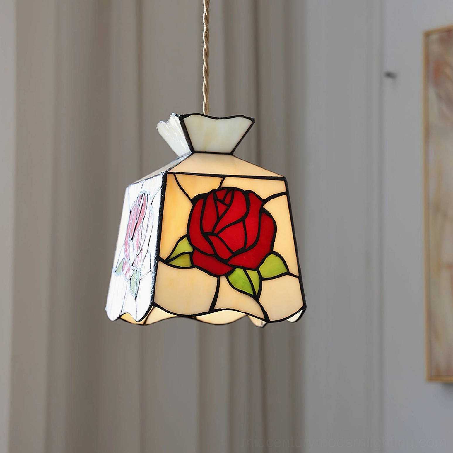 Rose pendant light with twisted rope cord hanging from ceiling, side view showcasing the warm glow through botanical stained glass