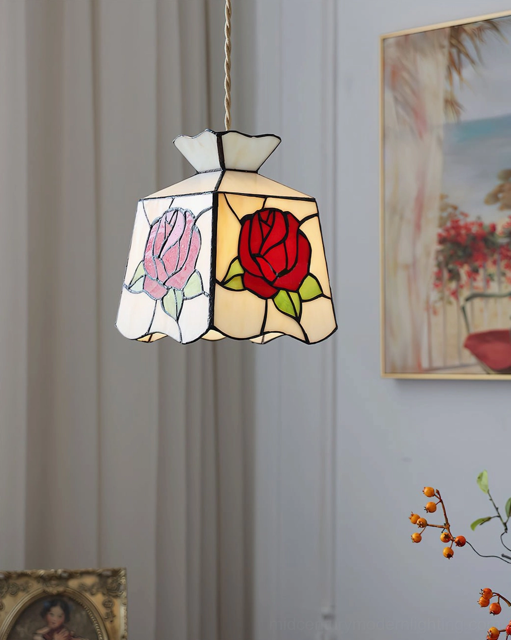 Rose stained glass Tiffany pendant lamp mounted against indoor wall with curtain backdrop, clear view of dual rose motifs