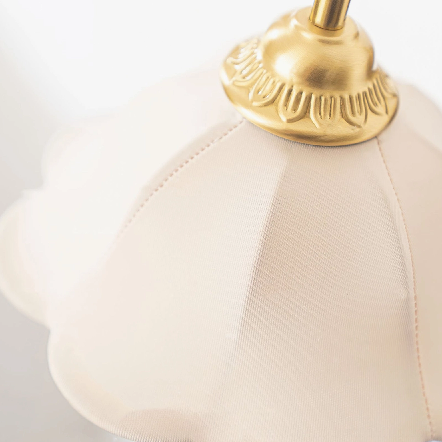 Close-up detail of scalloped fabric shade and decorative brass finial on Rosette wall sconce